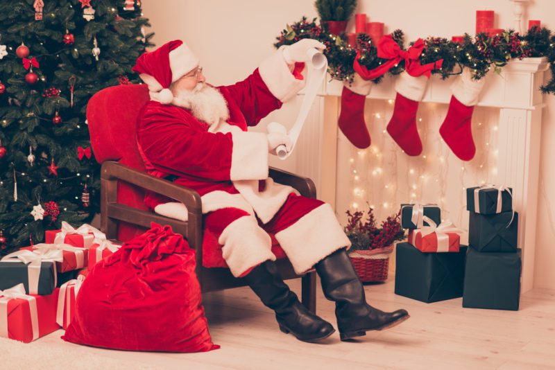 Santa reading a list of six cars for Santas stocking
